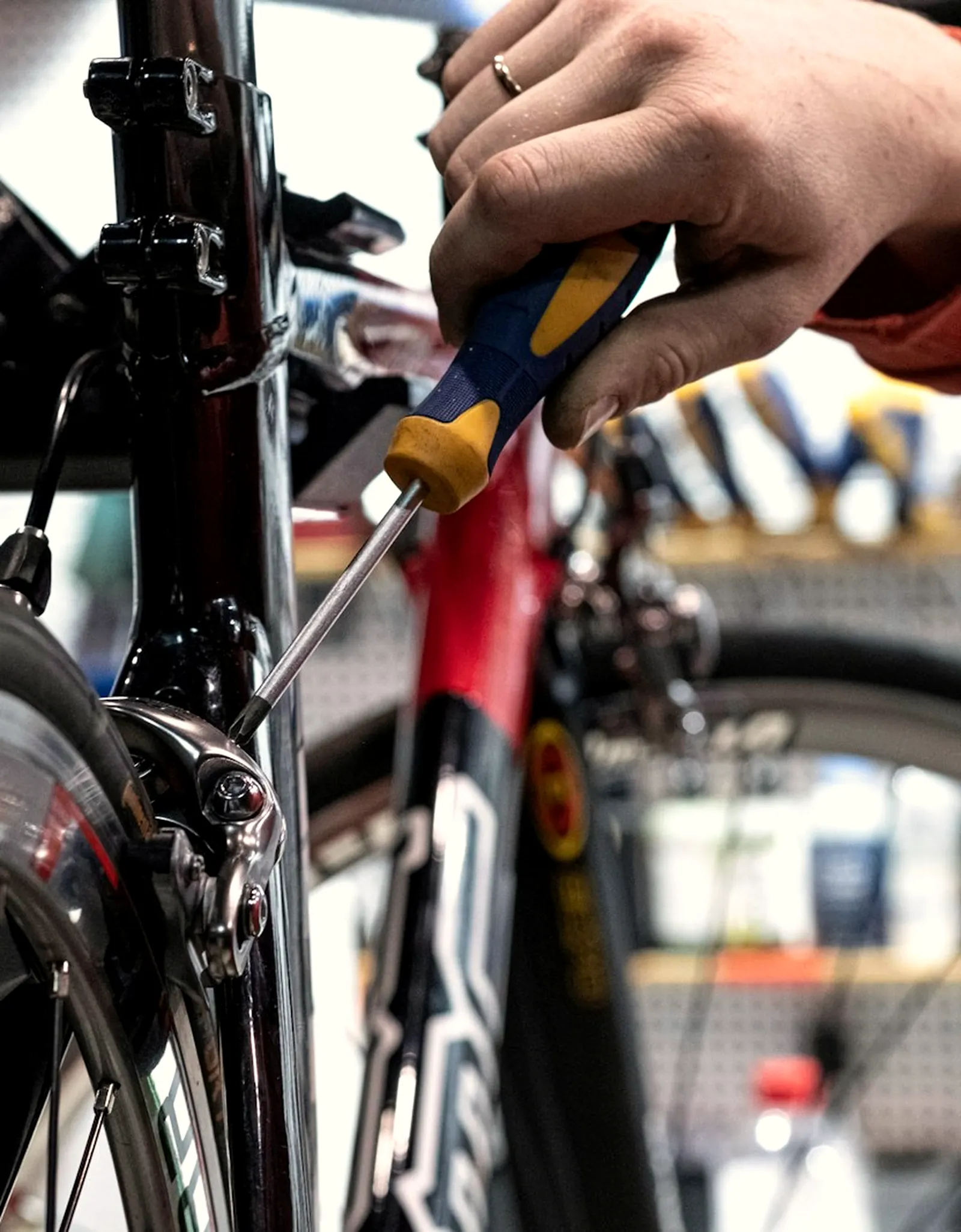 Mécanicien réglant un frein de vélo de route à l'établi, dans un atelier de réparation.