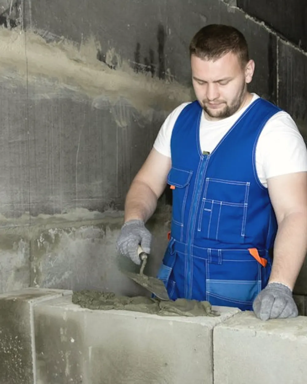 Maçon jointoyant un mur de parpaings à la truelle