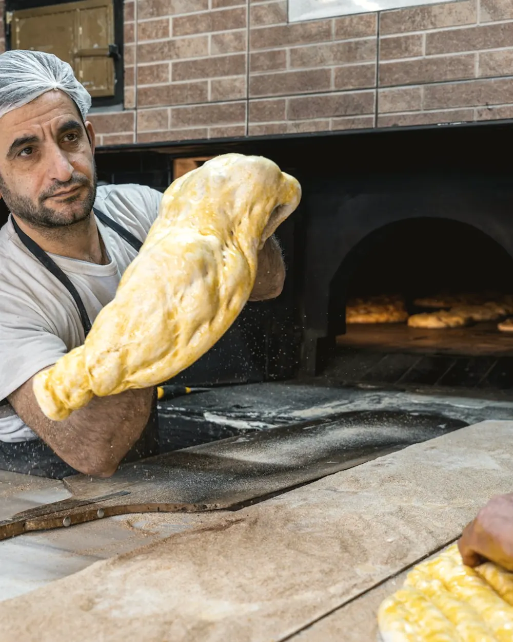 Pizza étirée à la main devant le four à bois