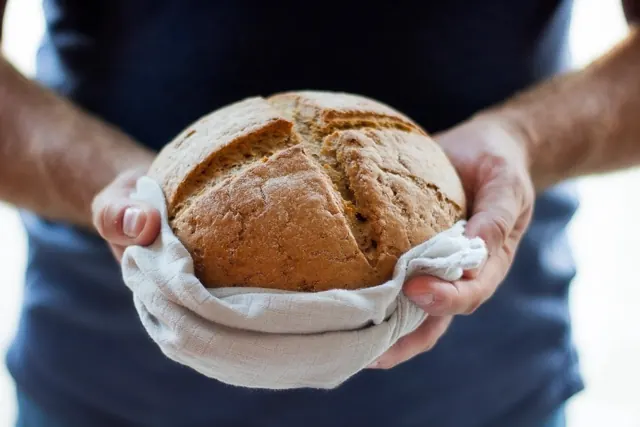 Deux mains tiennent une miche dans un torchon
