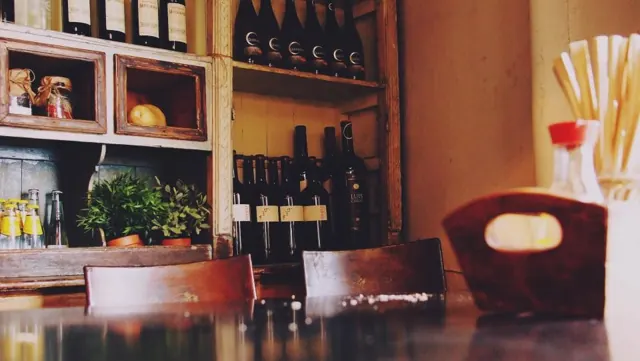Comptoir en bois sombre, étagères de bouteilles et de bocaux