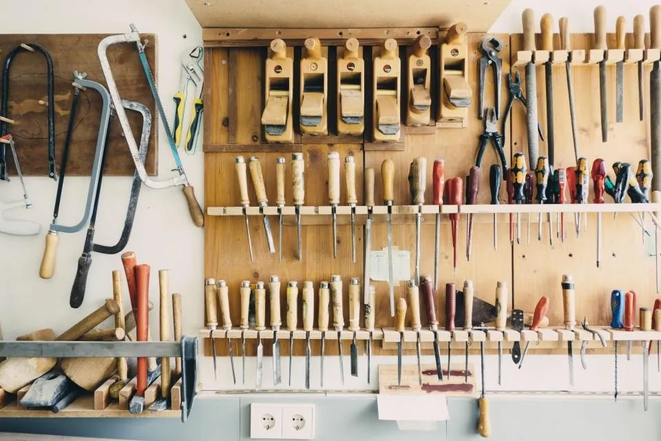 Mur d'atelier : rabots, ciseaux à bois et scies rangés sur des tasseaux