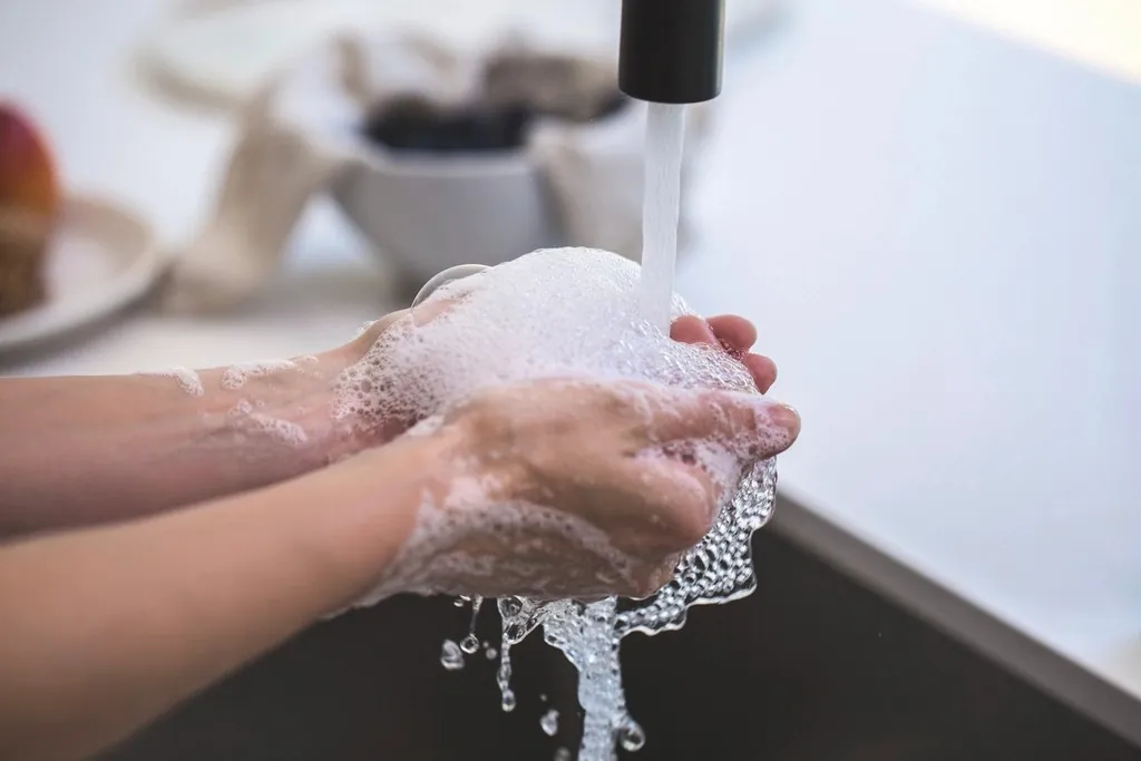 Des mains couvertes de mousse sous le robinet