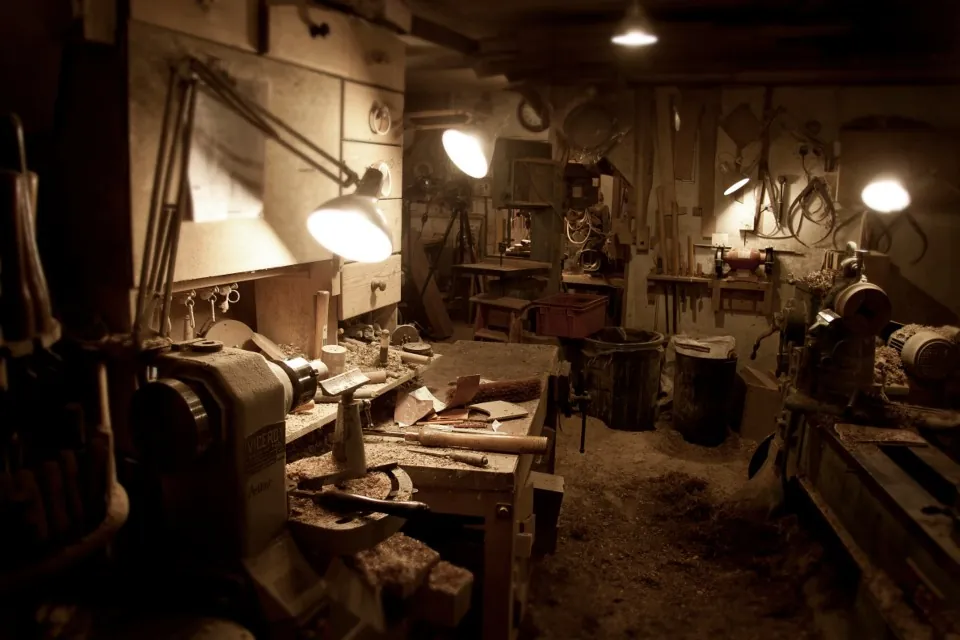 Atelier de menuiserie : établis, outils accrochés au mur, lampes allumées