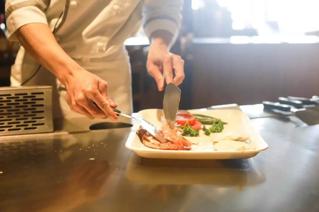 Un cuisinier dresse une assiette sur le passe en inox
