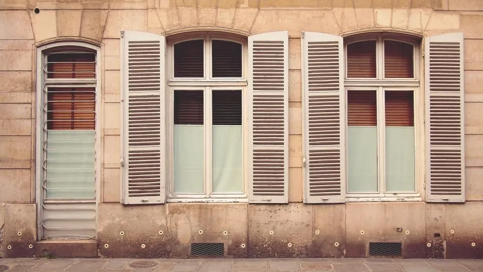 Façade en pierre claire, volets persiennés ouverts
