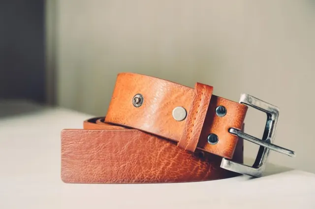 Gros plan sur une bande de cuir tanné végétal, sa couture et une boucle en acier
