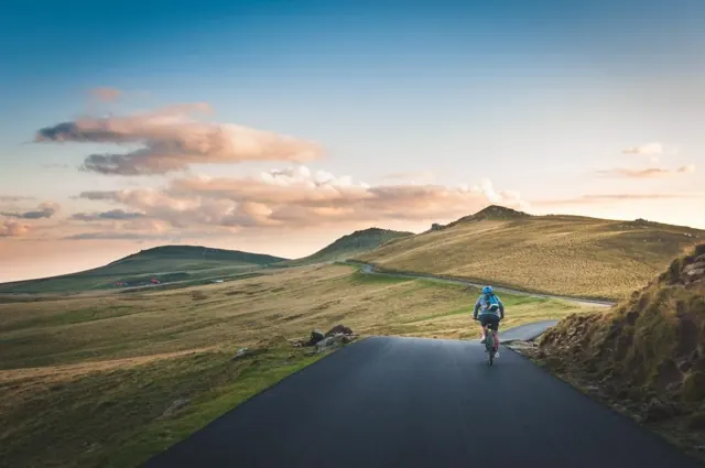 Un cycliste sur une petite route de montagne au coucher du soleil