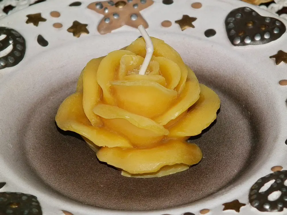 Bougie en cire d'abeille moulée en forme de rose, posée dans une coupelle