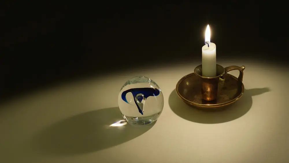 Flamme d'une bougie et sphère de verre qui en projette la lumière