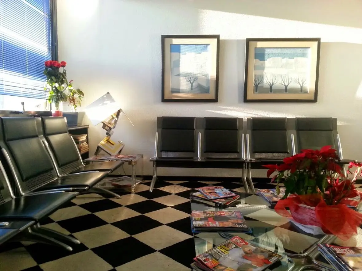 Salle de soins aux tables de massage alignées, éclairée par de hautes fenêtres