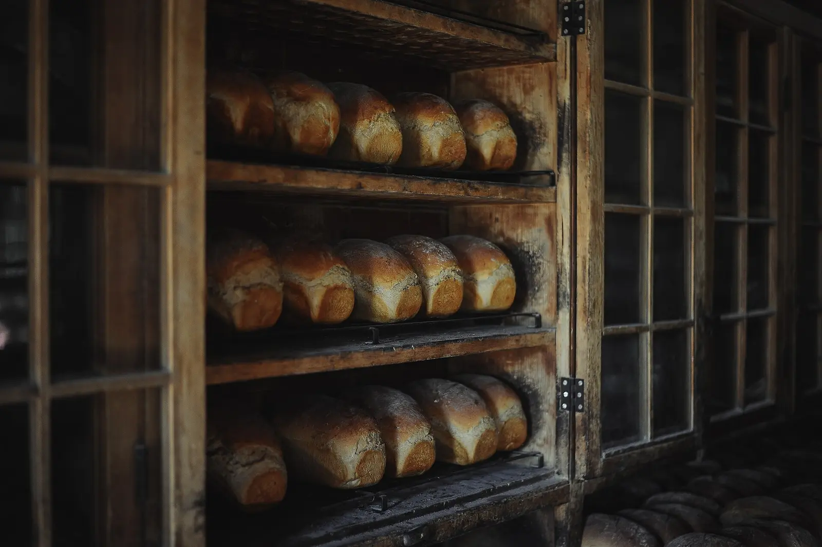Pains de mie alignés sur les clayettes en bois d'une armoire de boulangerie