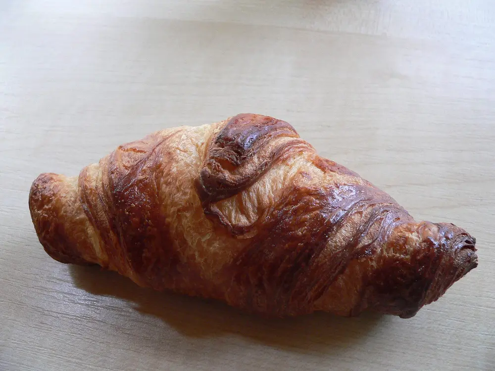 Croissant doré posé sur une nappe claire